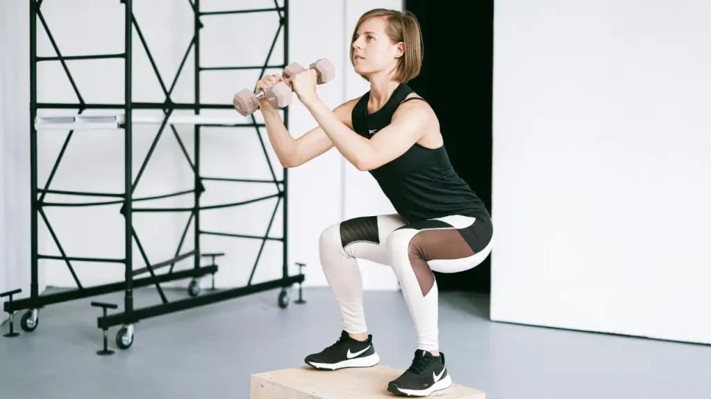 A woman exercising squats with dumbbells
