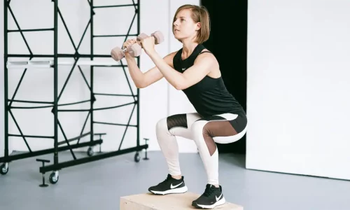 A woman exercising squats with dumbbells