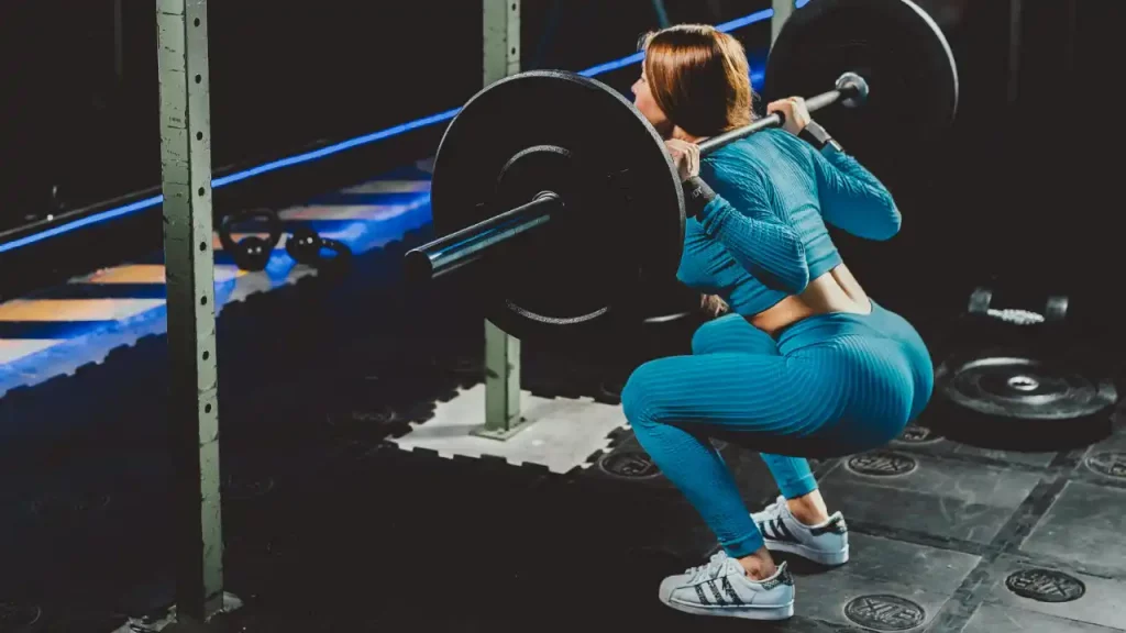 Woman performing a barbell back squat in a gym – strength training for women in Dubai